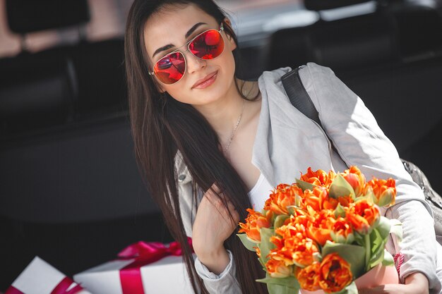 新鮮な花の花束を保持している春の若い美しい女性の肖像画。