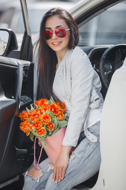 Portrait of young beautiful woman in spring holding a bouquet of fresh flowers.