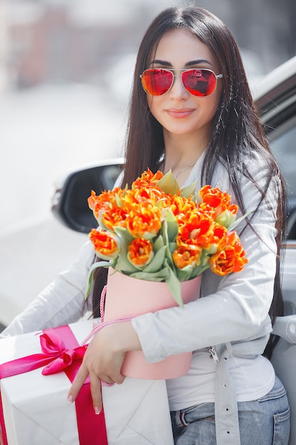 Ritratto di giovane bella donna in primavera che tiene un mazzo di fiori freschi.