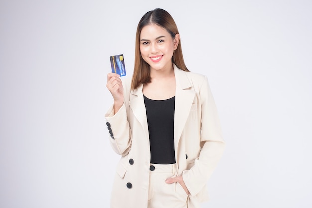 Portrait of Young beautiful woman in suit holding credit card over white  background in studio