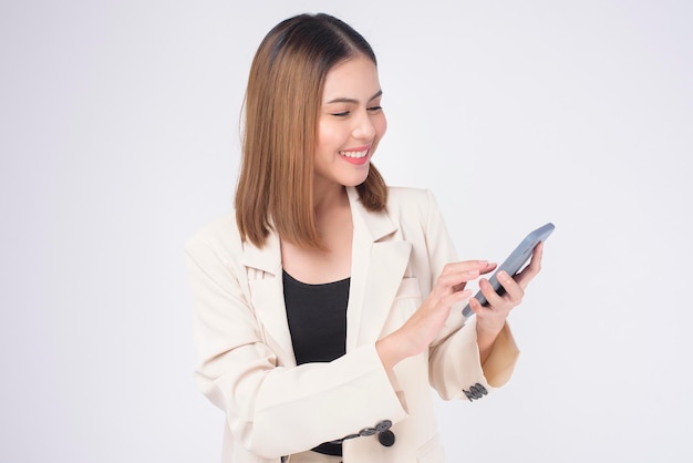 Portrait of young beautiful woman in suit using smart phone over white background