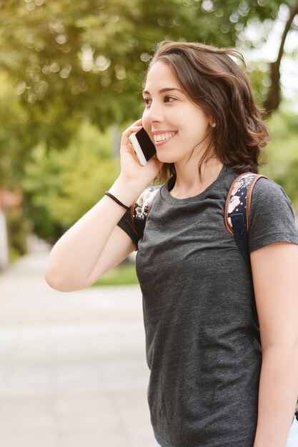 彼女のスマートフォンと話している若い美しい女性の肖像画