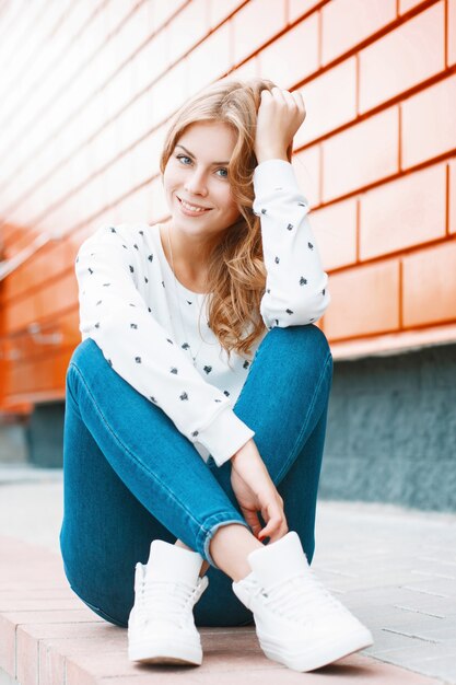 Portrait of a young beautiful woman in a white sweater jeans