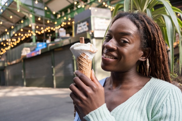 Foto ritratto di giovane bella donna con dreadlocks afro godendo un gelato in città