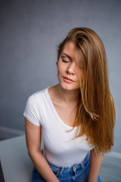 Портрет молодой красивой женщины со светлыми волосами европейской внешности, одетой в белую футболку Эмоциональное фото человека
