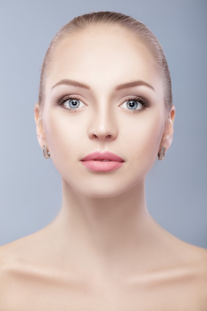 portrait of young beautiful woman with blue eyes  on blue background. everyday makeup