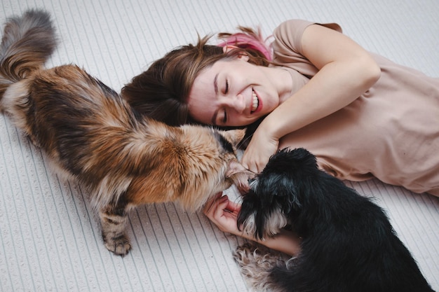 猫と犬を一緒に持つ若い美しい女性の肖像画