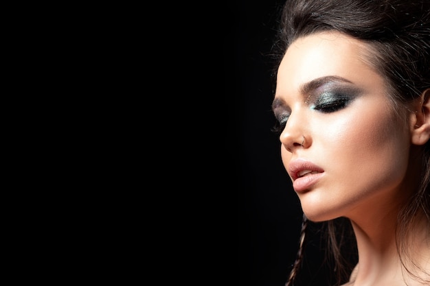 Portrait of young beautiful woman with evening make up model posing over black background