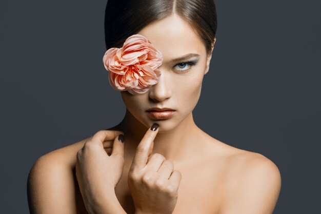Ritratto di giovane donna bellissima con un fiore negli occhi