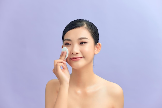 Portrait of young beautiful woman with healthy glow perfect smooth skin removing make up with cotton pad