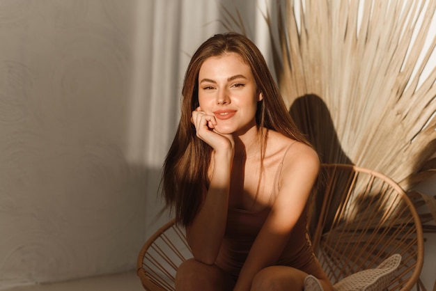 Portrait of a young beautiful woman with a healthy glow of perfectly smooth skin against the backdrop of a tropical leaf Organic natural cosmetics face and body skin care cosmetology concept