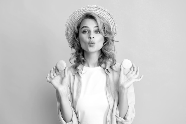 Portrait of young beautiful woman with macaroons French macaron Girl enjoying sweets isolated on yellow background