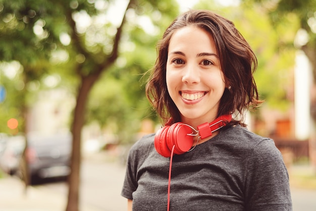 Portrait of young beautiful woman with red headphones listening music