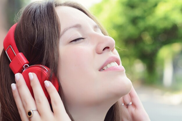 Portrait of young beautiful woman with red headphones listening 