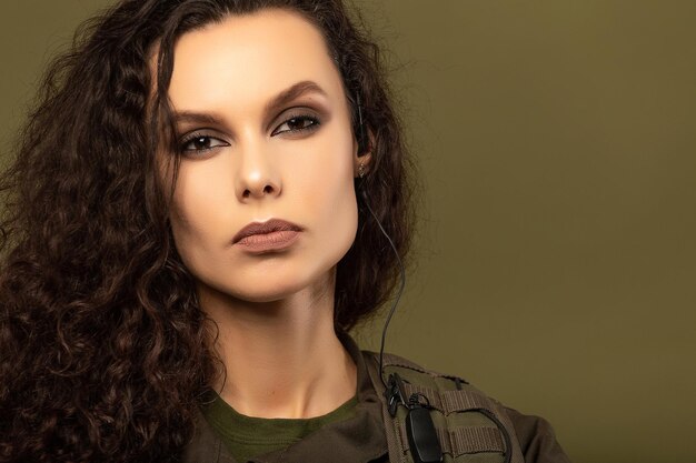 Portrait of young beautiful woman with serious expression on\
the face of military soldier