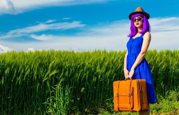 Portrait of young beautiful woman with suitcase in the field. summer time season concept