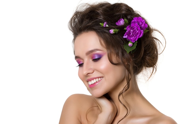 Portrait of young beautiful woman with violet flowers in her hair