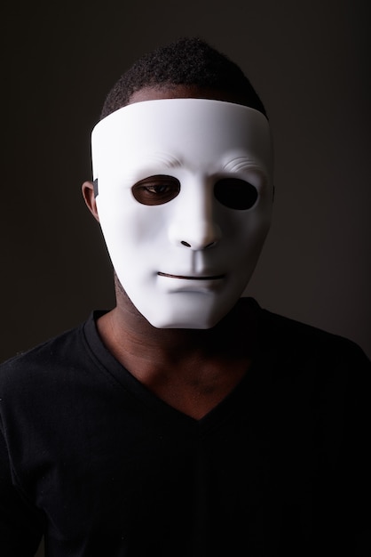 Portrait of young black African man in dark room wearing mask