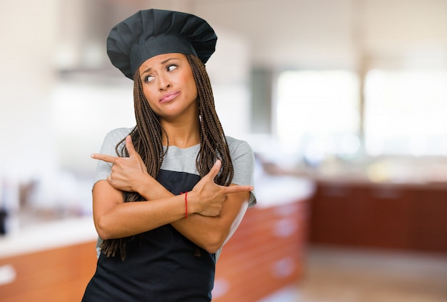 Portrait of a young black baker woman confused and doubtful man, decide between two options