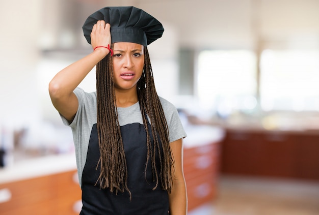 Portrait of a young black baker woman worried and overwhelmed, forgetful, realize something