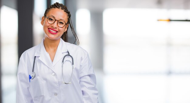 Ritratto di una donna giovane medico nero allegro e con un grande sorriso, fiducioso, amichevole e sincero, che esprime positività e successo