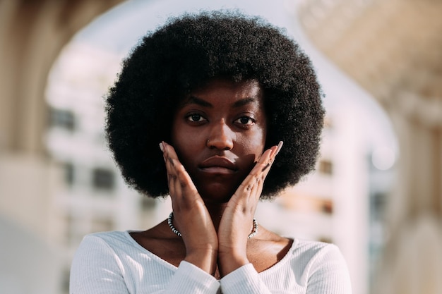 Ritratto di una giovane attivista nera con capelli afro che gesticolano con le mani a forma di av orizzontale