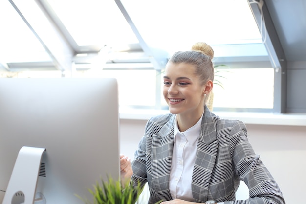 オフィスでコンピューターを使用して若い金髪のビジネス女性の肖像画。