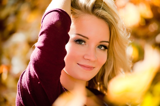 Portrait of young blond woman in autumn park. Fashion model with long straight hair