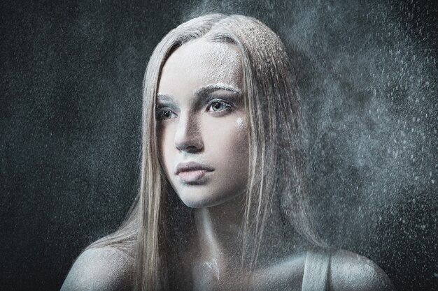 Portrait of young blond woman over snowy blizzard