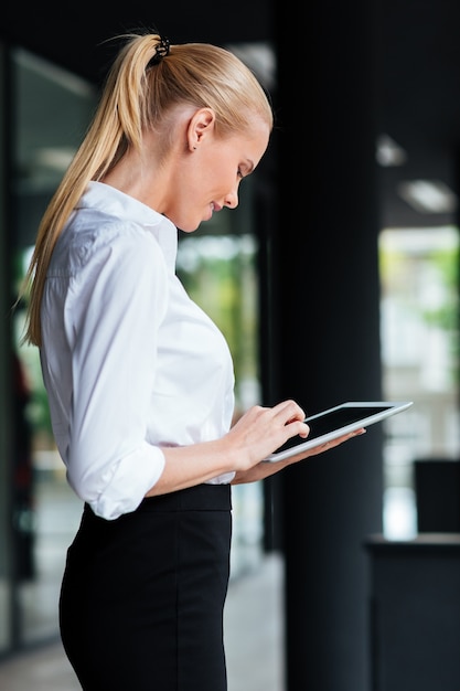 Portrait of a young blonde businesswoman using a digital tablet outdoors