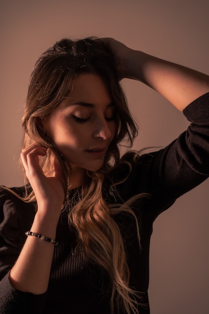 Portrait of a young blonde caucasian woman on a brown background with soft side light