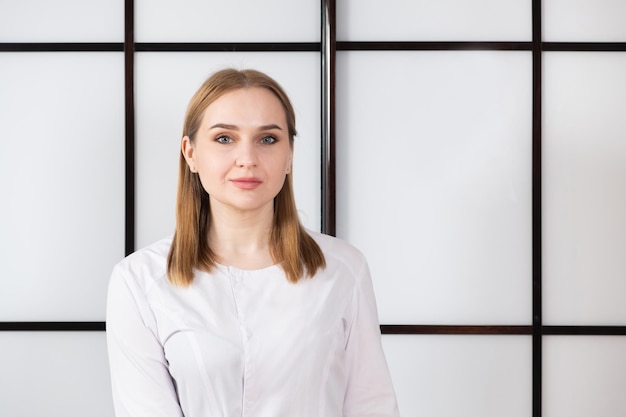 Portrait of a young blonde doctor in a white uniform on a black and white background