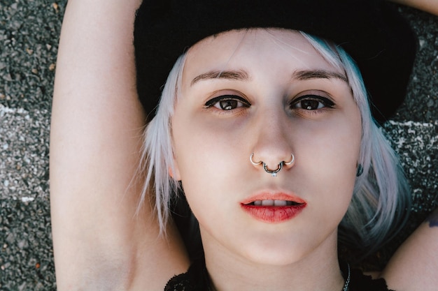 Portrait of a young blonde female with a piercing lying on the ground