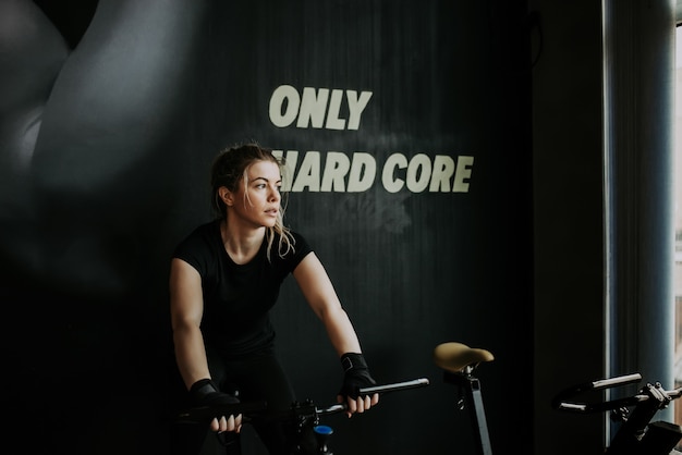 Portrait of a young blonde fit woman on exercise bike in the gym. Looking away.