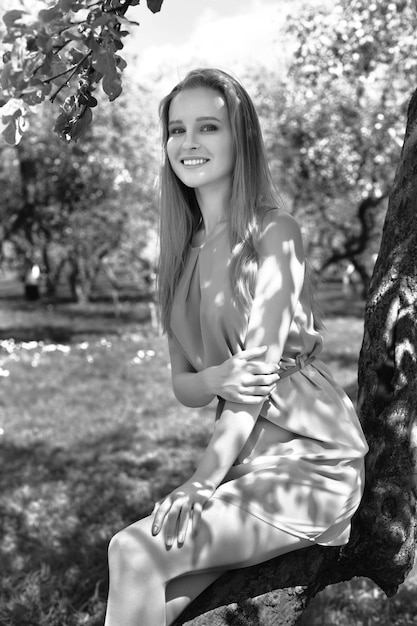 Portrait of a young blonde girl in a blue dress. trees in flowers.