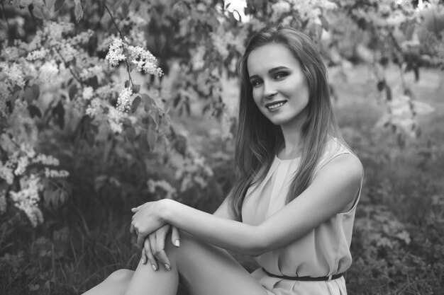 Portrait of a young blonde girl in a blue dress. trees in flowers.