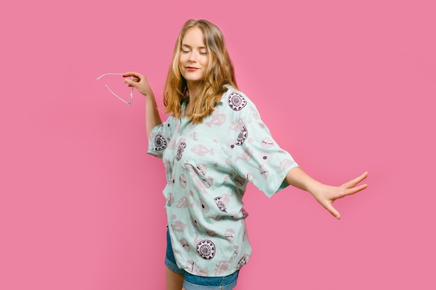 portrait of a young blonde girl dancing on a pink background