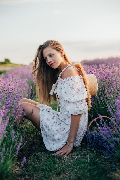 Ritratto di una giovane ragazza bionda in un campo di lavanda in estate al tramonto