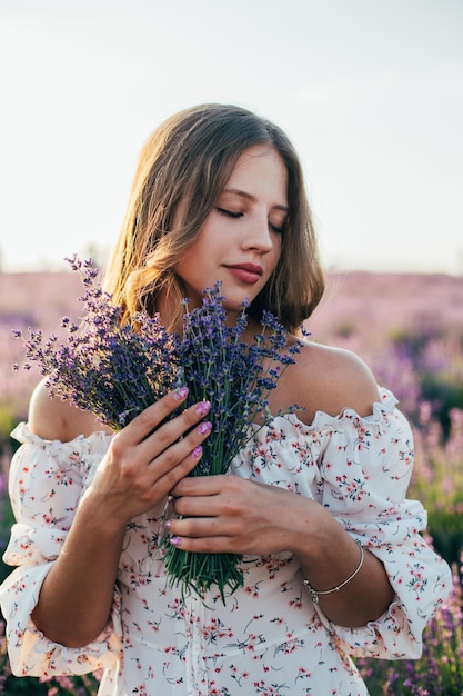 Portrait of a young blonde girl in a lavender field in the summer at sunset