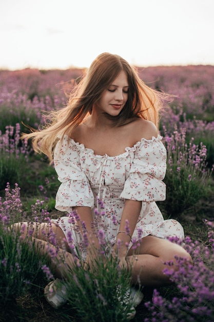 Portrait of a young blonde girl in a lavender field in the summer at sunset
