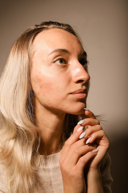 Portrait of a young blonde girl without makeup with loose hair hands folded near her face