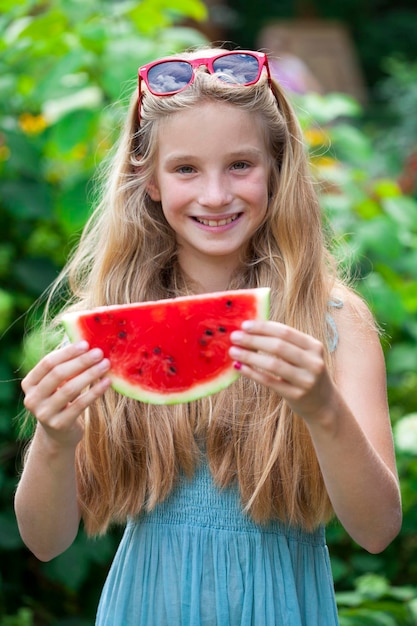 Photo portrait of a young blonde little girl with watermelon, summer outdoor