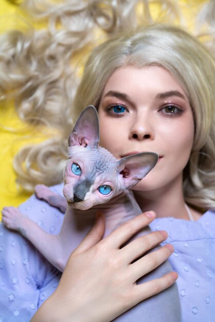 Portrait of young blonde woman cosplay elf with eyes of different colors holding blue eyed kitten