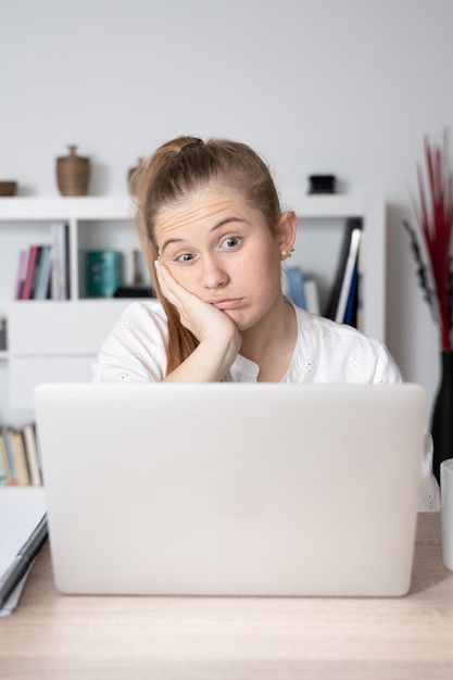 Portrait of young blonde woman in front of laptop