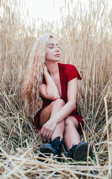 Portrait of young blonde woman in wheat field in summer