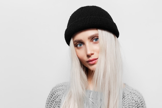 Photo portrait of young blonde woman with blue eyes wearing black beanie hat.