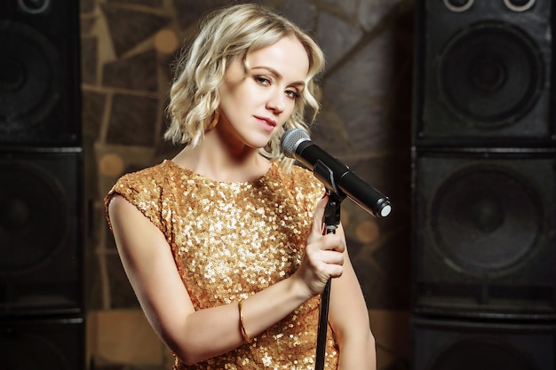 Photo portrait of young blonde woman with microphone on dark