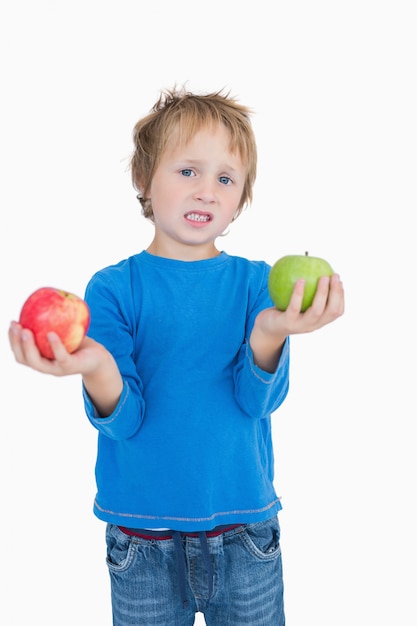 Portrait of young boy holding out green and red apples