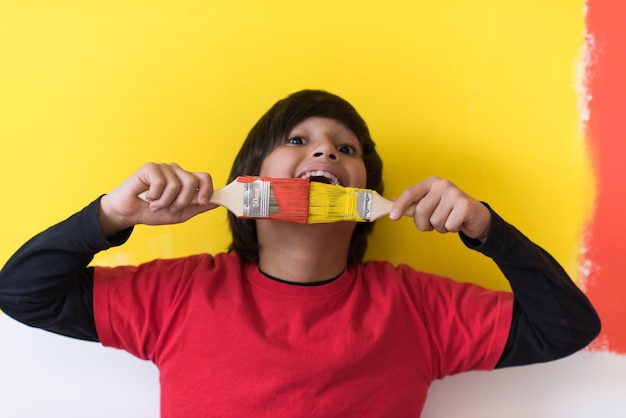 Portrait of a young boy painter with a brushes in his hands in front of colored background