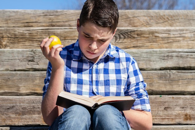 Portrait.Young boy reading a book in wooden stairs, summer